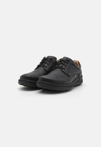 Black leather lace-up shoes with rounded toe, contrasting stitching, and cushioned sole. Features smooth texture and minimal branding.