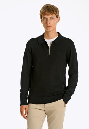 Sorte zippered polo sweater med lange ærmer, ribbede manchetter og kant, lavet af blødt stof; båret over en hvid skjorte. Minimalistisk logo detalje.