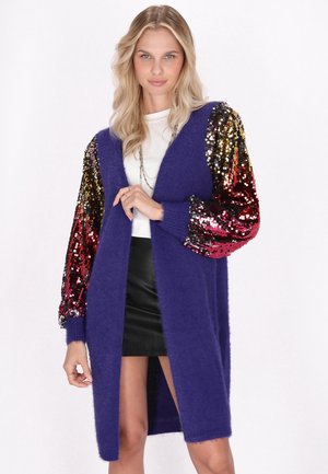 Paarse fuzzy cardigan met glanzende, multicolore pailletten mouwen. Heeft een diepe V-hals en een open voorkant ontwerp. Korte, rechte zoom.