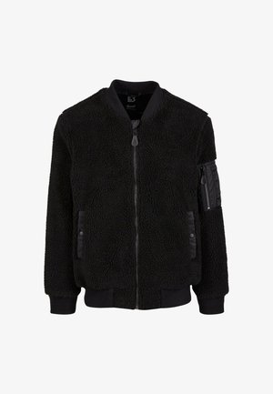 Czarna kurtka bomberka z sztucznego futra, z zamkiem błyskawicznym, ściągaczami na rękawach oraz dwiema przednimi kieszeniami. Posiada kieszeń na ramieniu z zamkiem i akcentem z tkaniny.