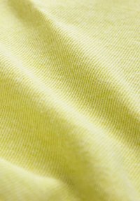 Tessuto giallo chiaro con una trama fine e strutturata. La superficie è liscia e mostra sottili variazioni di colore e texture.