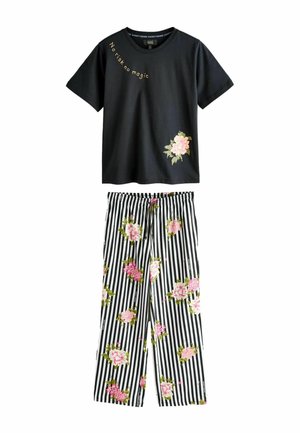Černá krátká košile s nápisem "No risk no magic" a růžovým květem, doplněná černobílými pruhovanými kalhotami s růžovými květinovými vzory.
