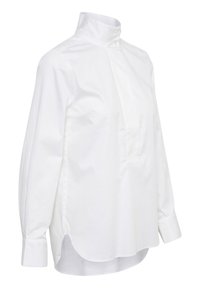 Cămașă albă cu mânecă lungă, cu guler înalt, cu o deschidere cu butoane, croială dreaptă și slituri laterale pentru ușurința în mișcare.