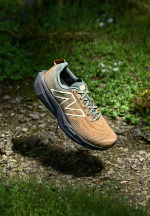 Lightweight running shoe with a breathable mesh upper in tan and green, featuring a textured sole, contrasting white logo, and orange accent.