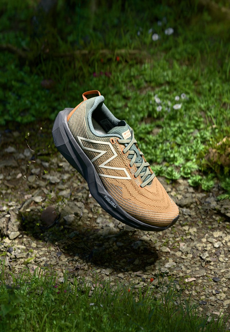 Scarpa da corsa leggera con tomaia in mesh traspirante nei toni del beige e verde, dotata di una suola texturizzata, logo bianco a contrasto e accentuazioni arancioni.