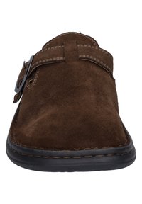 Brązowy zamszowy but wsuwany z okrągłym noskiem, kontrastowym przeszyciem, metalowym akcentem w postaci klamry oraz elastyczną czarną gumową podeszwą.