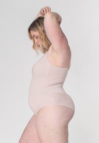 Nackter Bodysuit mit Spitzenakzenten, glattem Stoff, ärmellosem Design und tailliertem Schnitt, der eine Seitenansicht mit floralen Spitzenmotiven zeigt.