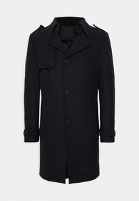 Cappotto in misto lana nero con chiusura doppiopetto, grandi bottoni, ampio colletto e spalline. Presenta due tasche laterali e dettagli sui polsini.