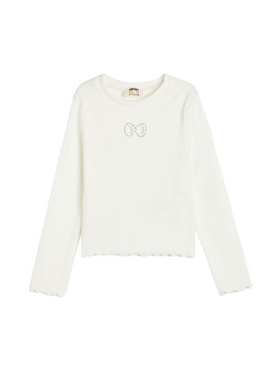 Chemise blanche à manches longues en tissu côtelé, avec un ourlet festonné et un petit nœud décoratif au niveau de la poitrine.