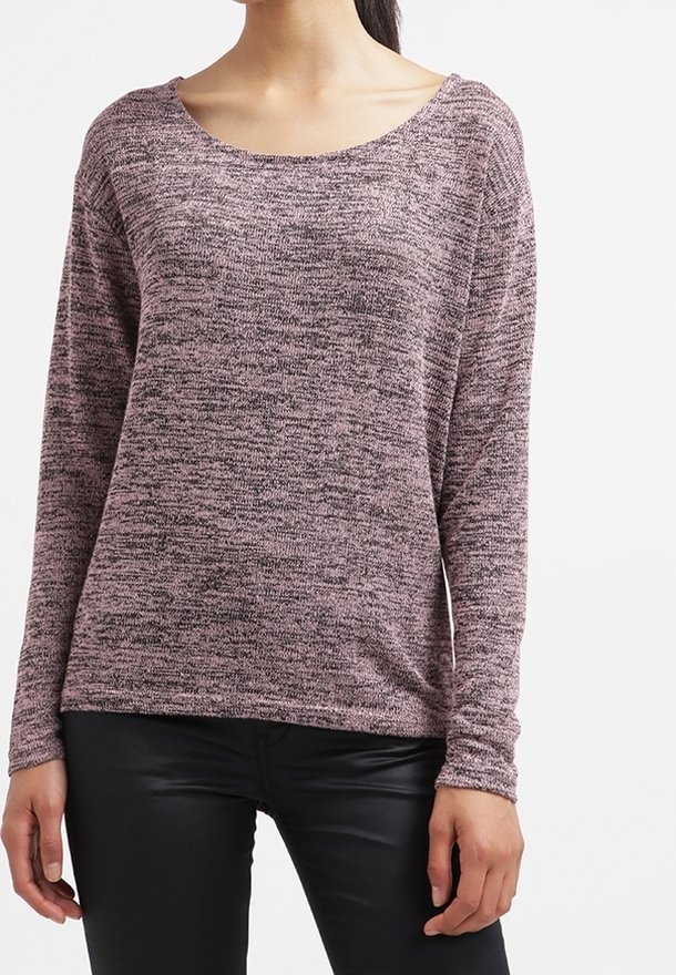 Femme portant un pull en maille chiné rose et noir à manches longues avec un pantalon en cuir noir sur un fond blanc.