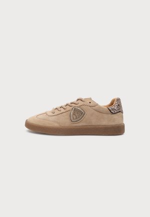 Μπεζ παπούτσι sneaker από σουέτ με καφέ λαστιχένια σόλα, διακοσμητικό με χάντρες στο πλάι και γκλίτερ λεπτομέρεια στη φτέρνα, σε προφίλ πάνω σε λευκό φόντο.