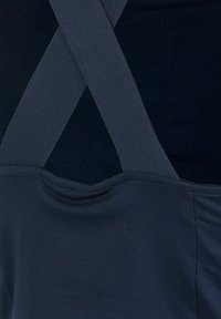 Marineblauwe kledingstukken met gekruiste banden, een gladde textuur en een ronde halslijn. Gestikte naden voegen subtiele details toe aan de stof.