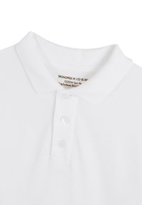 Polo shirt blanc pour enfants en coton biologique. Présente un col classique, une patte de boutonnage à trois boutons et un tissu texturé doux.