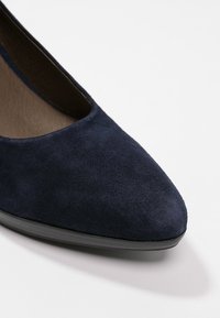 Tacco in camoscio blu navy con design a punta, texture liscia e suola sintetica nera. Nessun hardware o accento visibile.