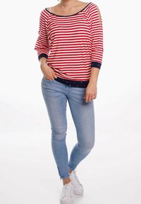 Rød og hvid stribet trekvartærmet top med marineblå detaljer, parret med lyseblå skinny jeans og hvide sneakers.