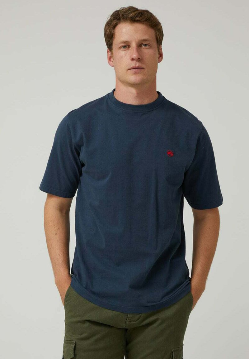 Camiseta de algodón de color azul marino con mangas cortas, diseño de cuello redondo y un pequeño detalle de logo rojo en el pecho izquierdo. Textura de tela suave.