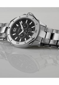 Montre en acier inoxydable argenté avec un cadran noir, grands marqueurs d'heure blancs, trois sous-cadrans et un bracelet en métal brossé. Résistante à l'eau jusqu'à 50 m.