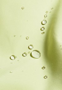 Wasserabweisender Stoff in Hellgrün, der verschiedene Größen von Wassertropfen auf einer glatten Oberfläche zeigt und die Textur sowie die Materialqualität hervorhebt.