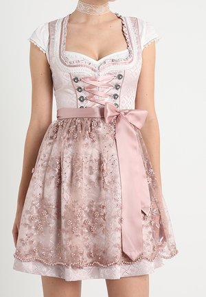 Kvinde iført en lyserød traditionel dirndl kjole med snørret korsage, blomsterbroderet forklæde og en satin sløjfe bundet i taljen.