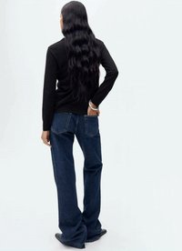 Black long-sleeve top paired with blue wide-leg jeans. The jeans have a faded texture and two back pockets. Model has long, wavy hair.