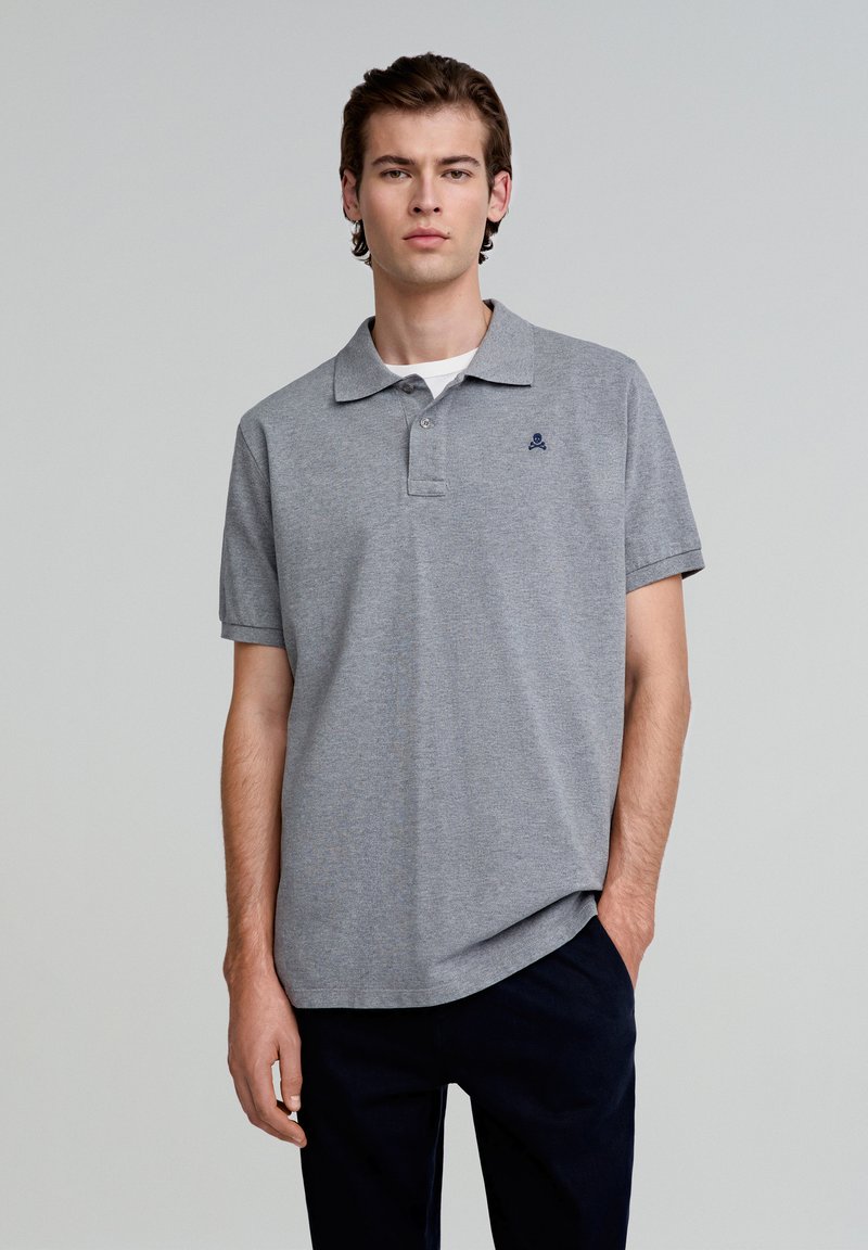 Grijze polo gemaakt van zachte stof, met een klassieke kraag, korte mouwen en een klein navy-logo op de borst.