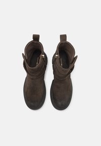 Brune mokkasiner ankler med rund tå, svarte gummisåler og glidelåser på siden. Har en brettet mansjett og minimalistisk design.