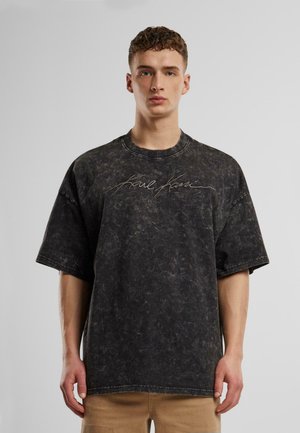 Oversized black cotton t-shirt with a textured finish and signature embroidery at the chest. Features a crew neckline and short sleeves.