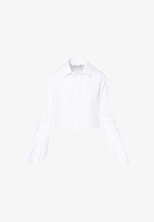 Bela skrajšana majica s ovratnikom in nagubanimi, razširjenimi rokavi. Ima zaklepanje na gumb ter vezi na zapestju. Iz bombažnega materiala.