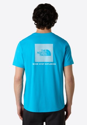 Blauw T-shirt met korte mouwen, met een vierkante afbeelding op de rug waarop het 'The North Face' logo staat en de tekst "NEVER STOP EXPLORING" daaronder.
