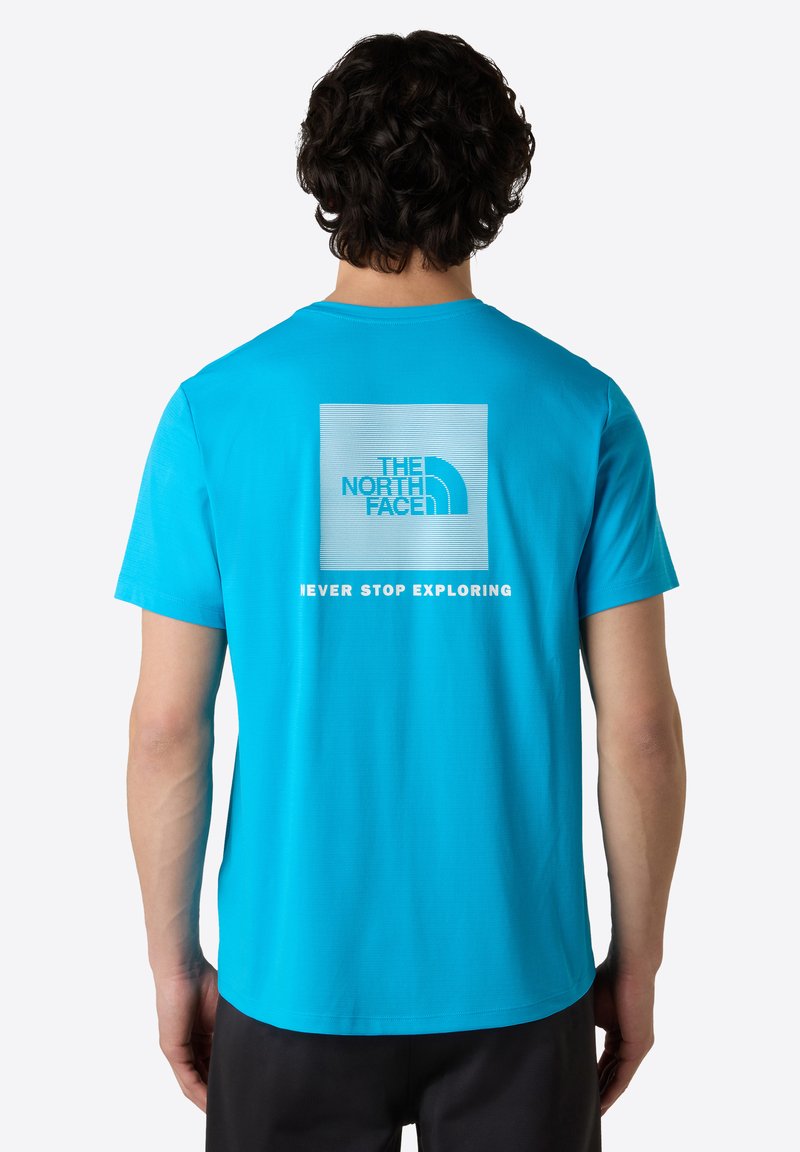 Kortärmad blå t-shirt med en fyrkantig grafik på ryggen som har "The North Face"-logotypen och texten "NEVER STOP EXPLORING" nedanför.