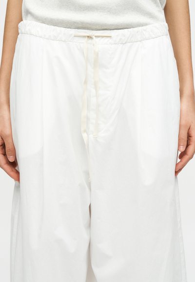 Άσπρο παντελόνι με άνετη εφαρμογή, με ελαστική μέση και κορδόνι. Κατασκευασμένο από ελαφρύ ύφασμα, διαθέτει απαλή υφή και πλαϊνές τσέπες.