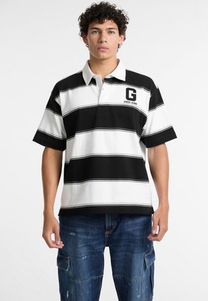 Čierno-biely pruhovaný polo tričko s golierom. Obsahuje logo "G" a text "GUESS JEANS"; krátke rukávy, uvoľnený strih.