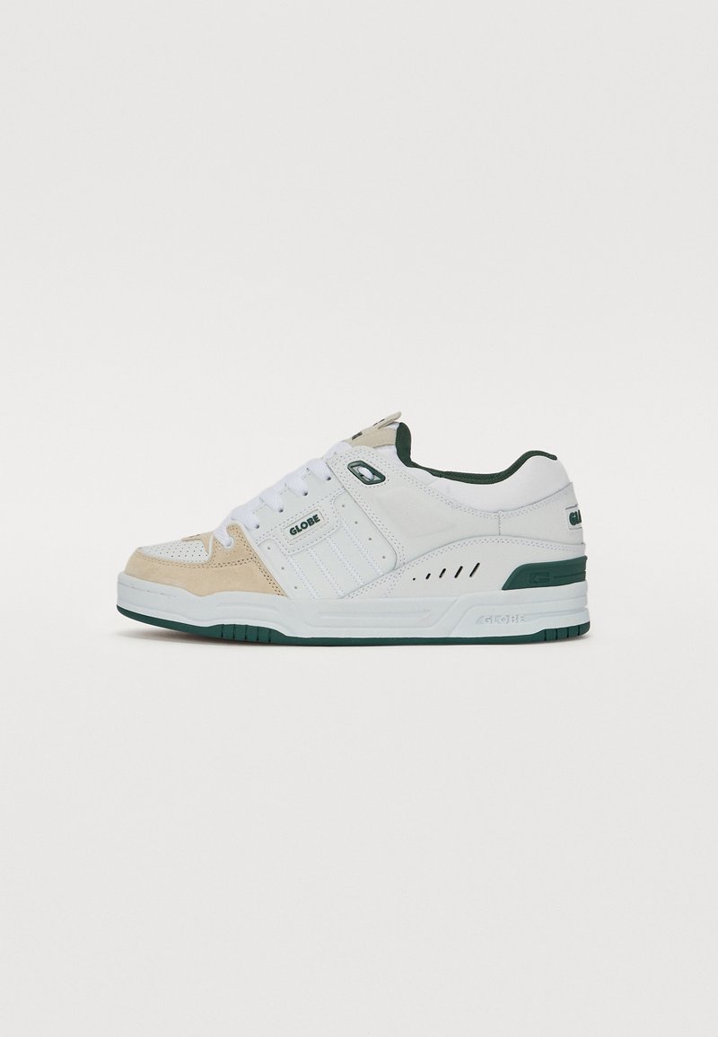 White and beige sneaker with a textured suede and mesh upper, green accents, lace-up design, and rubber sole with patterned tread.