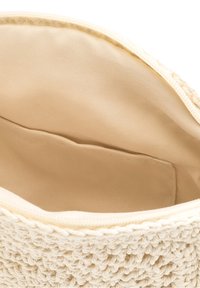 Beige virkade påse med en texturerad utsida och slät inredning. Har en dragkedjestängning och ett ensamt innerfack.