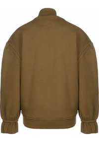 Khaki mikina s vysokým golierom, voľným strihom a zberanými manžetami. Mäkká textúra a minimalistický dizajn posilňujú jej ležérny vzhľad.