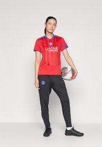 Röd fotbollsdräkt med blå detaljer, med "QATAR AIRWAYS"-logotyp och vertikala ränder. Svarta byxor med blå detaljer. Svart fotboll ingår.