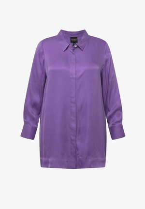 Szczotkowana purpurowa bluzka z kołnierzykiem, długimi rękawami i zapięciem na guziki. Posiada dekoracyjny akcent w postaci guzika na kołnierzyku.