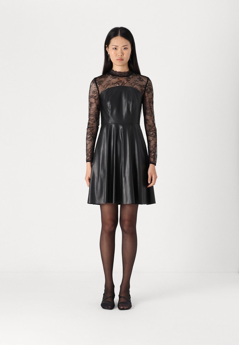 Robe noire avec un corsage ajusté, des manches longues en dentelle, une jupe évasée et une texture lisse semblable au cuir.