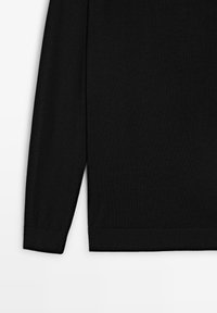 Top nero a maniche lunghe realizzato in tessuto morbido, caratterizzato da una vestibilità comoda e polsini a coste. L'orlo ha una leggera curva per un tocco moderno.