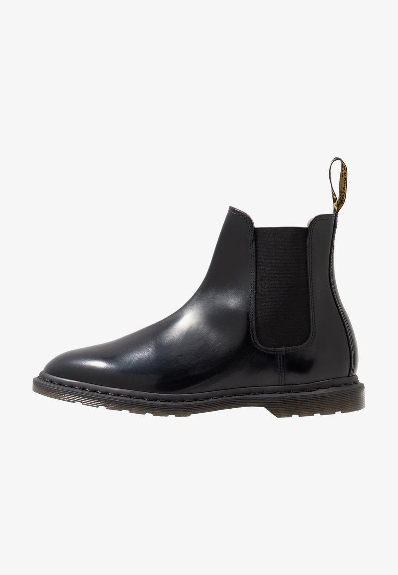 Botte Chelsea en cuir noir lisse avec panneau latéral élastique, semelle épaisse et languette à l'arrière avec branding jaune et noir.