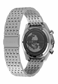 Montre en acier inoxydable avec un bracelet en métal argenté à motif tressé, un cadran noir gravé d'une carte du monde et des boutons sur le côté.