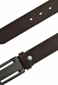Bruine leren riem met een gladde afwerking, voorzien van een metalen gesp. Zichtbare gaatjes voor aanpassing en een merkaccent in cirkelvorm dicht bij de gesp.