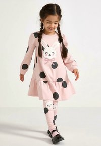 Rosa Kleid mit weißen Punkten und gerafftem Saum, vorn mit einem Hasenmotiv. Passende Leggings mit Hasengesichtern und Punkten.