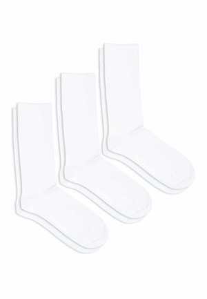 Tre par hvide bomuldsokker med ribbet design ved skaftet, som har forstærket tå og diskret branding på siden.