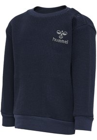Mörkblå sweatshirt i strukturerad tyg, med rund hals och tryckknappar på axeln. Litet broderat emblem på bröstet.