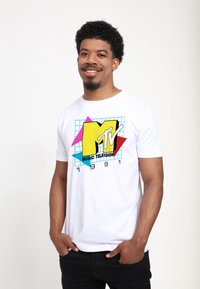 White cotton t-shirt featuring a colorful MTV logo with geometric shapes and text "MUSIC TELEVISION 1981" in bold black. Simple crew neck design.