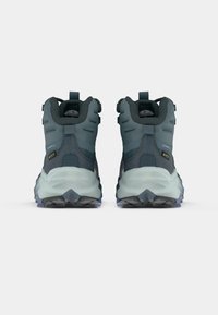 Botas de caminhada em teal escuro com acabamento texturizado, material impermeável, sola em borracha e colarínho de suporte ao tornozelo. Apresenta um calcanhar reforçado.