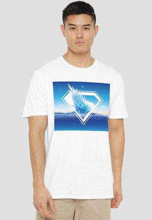 Young man wearing a white T-shirt with a blue geometric crystal design and the text "Take me home" on the chest.