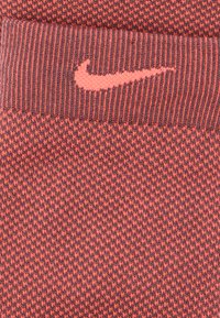 Πλεκτός σκούφος με υφή σε σκούρο κόκκινο και έντονο κοραλί. Διαθέτει λογότυπο Nike σε κοραλί στο μπροστινό μέρος. Μαλακό και ελαστικό υλικό.