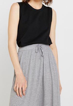 Haut sans manches noir associé à une jupe rayée grise et blanche avec une taille élastique et un cordon de serrage, créant une tenue décontractée.